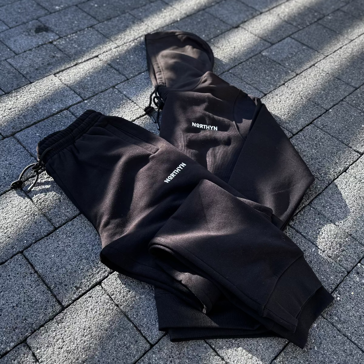 Black pants and a black Hoodie with 'NORTHYN' branding on a paved surface