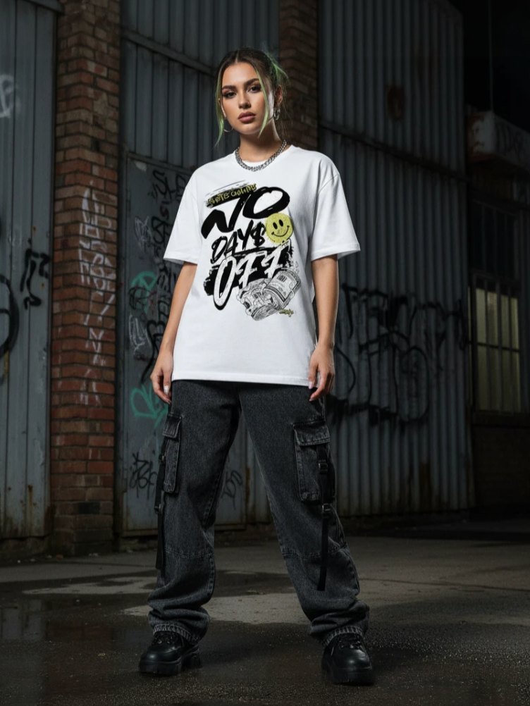 Person wearing a white t-shirt with graphic design in an urban setting with graffiti.